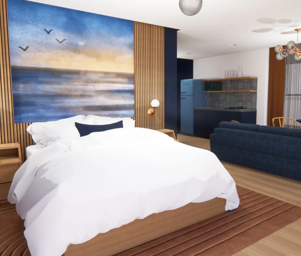 Modern bedroom with a large bed, abstract ocean artwork, wooden accents, and a view of a kitchenette and navy blue sofa in the background.